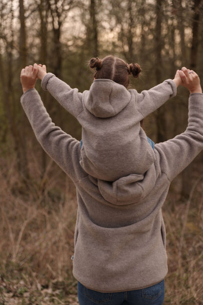 Woman and child wearing matching gray hoodies standing in a forest