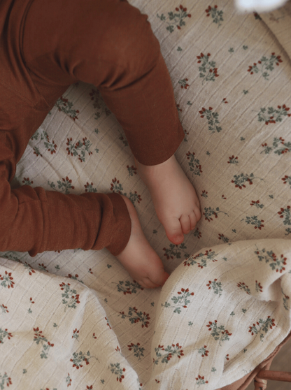 baby legs wearing brown leggins made from merino wool and silk on a blanket with flowers 