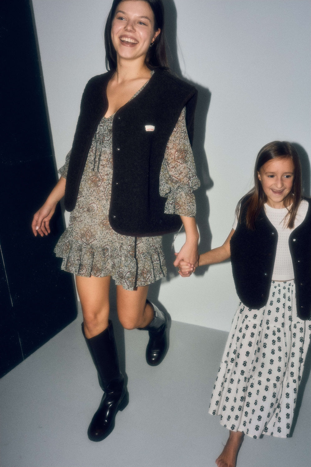 Woman and girl in matching outfits with brown vests and skirts
