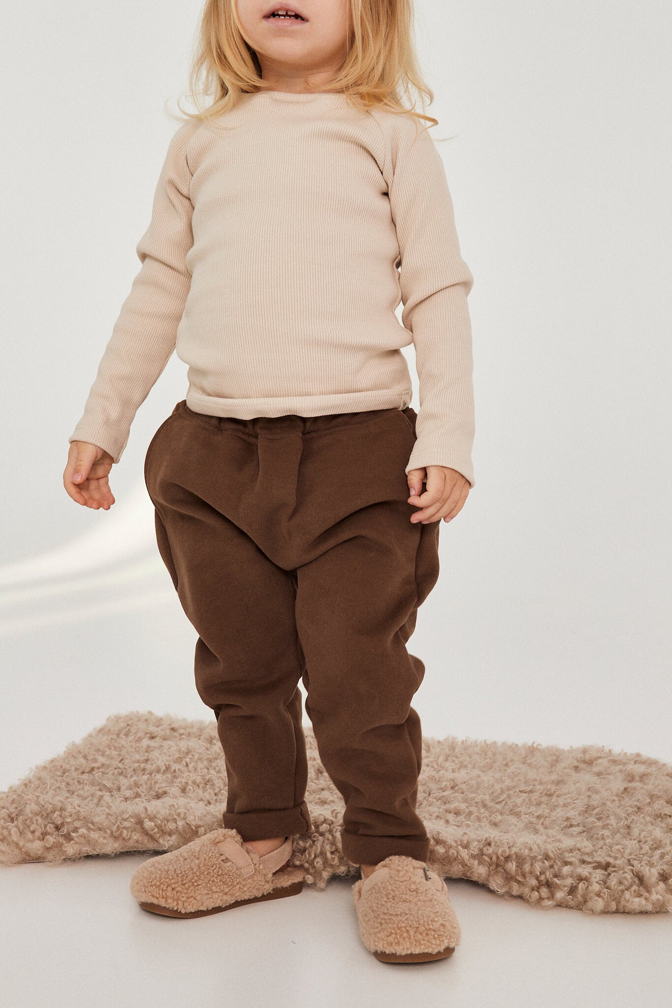 Child wearing a beige sweater and brown pants