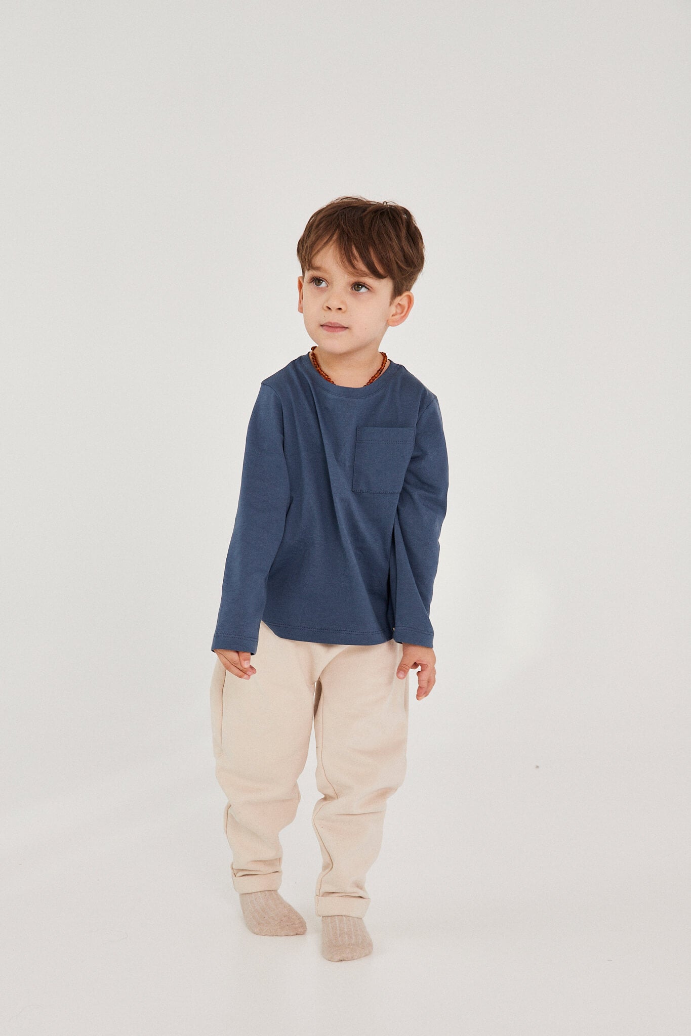 Child wearing a long-sleeved blue denim t-shirt and beige pants