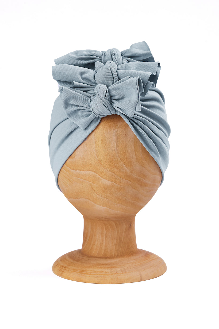 a light blue baby and toddler turban on a wooden mannequin with a white plain background