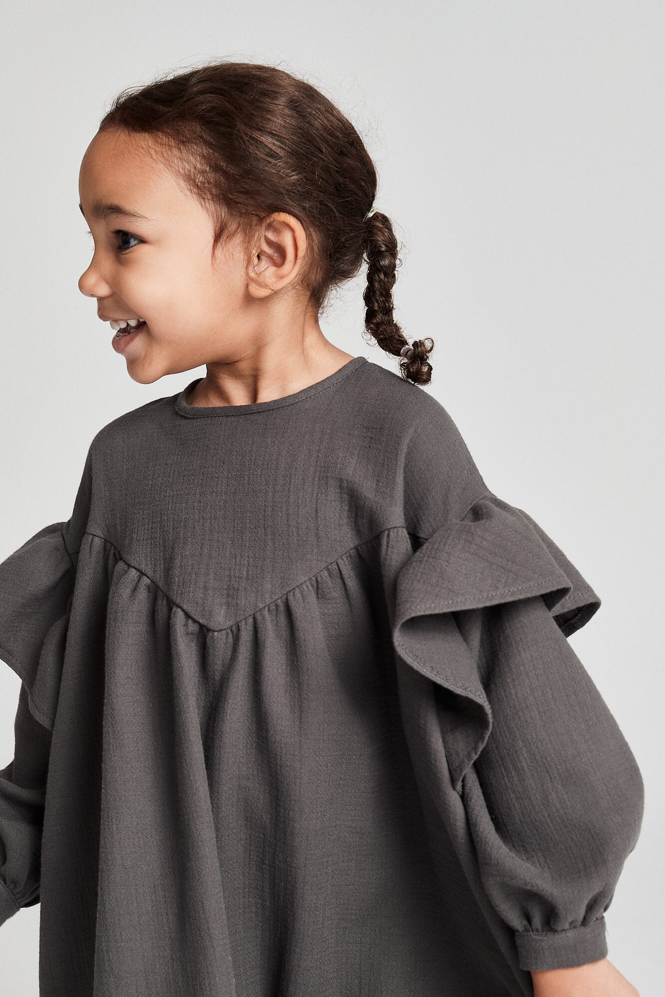 Child wearing a gray dress with ruffled sleeves