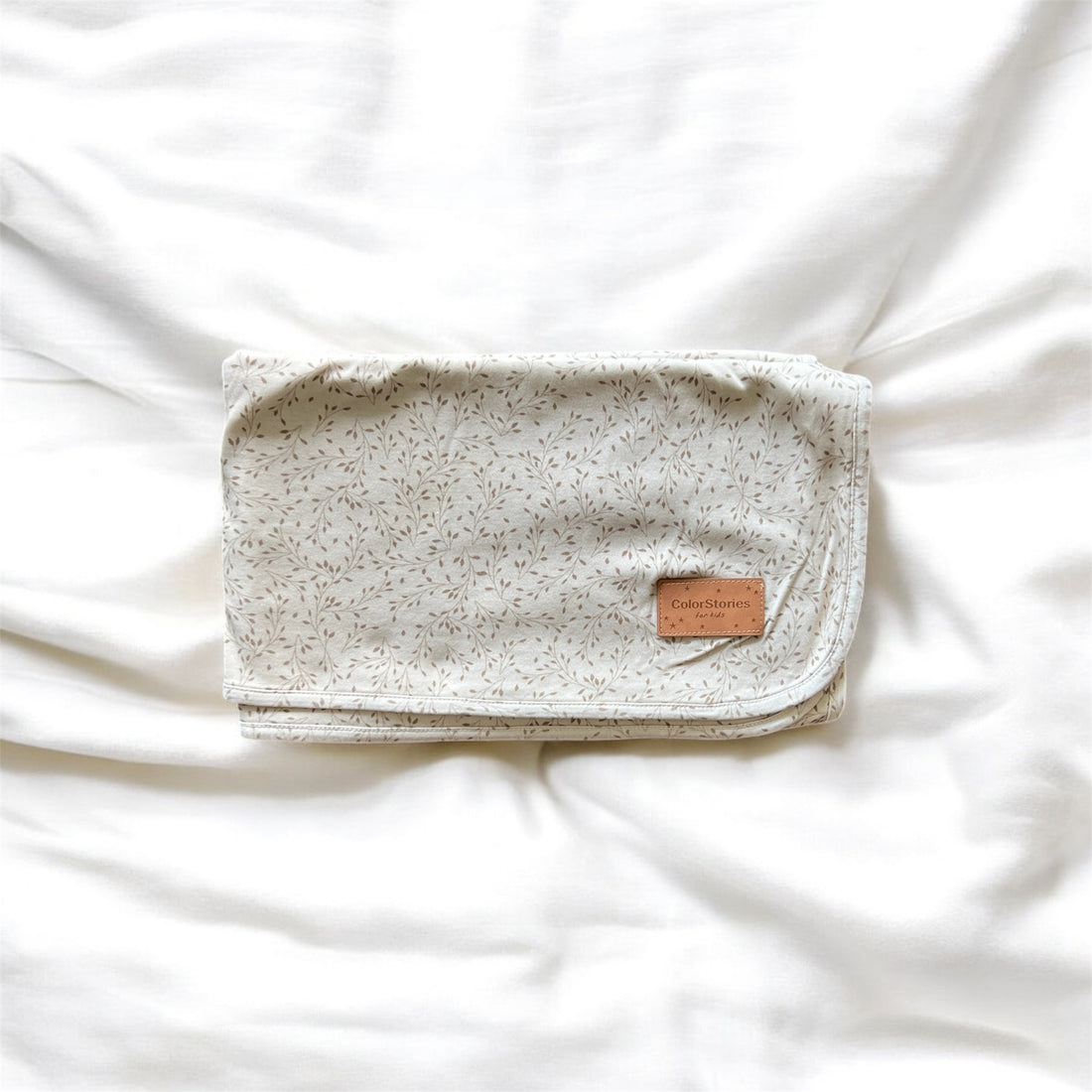 Baby blanket with flower pattern with a leather tag on a white background