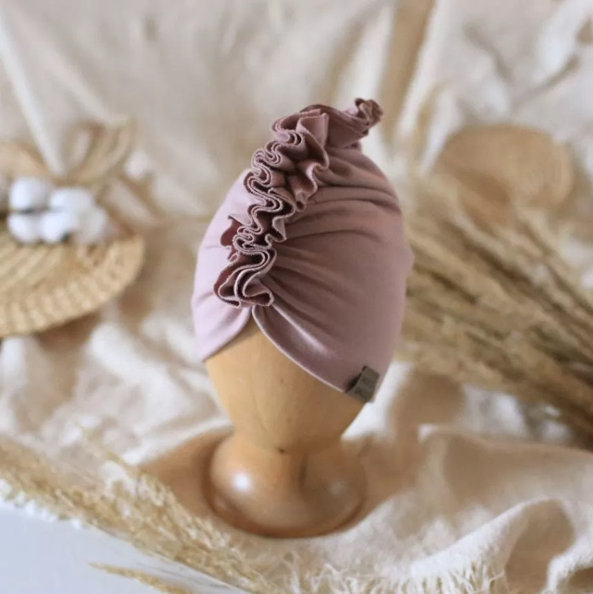 baby turban in color dusty pink on a wooden head mannequin