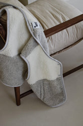 Gray and white patterned blanket draped over a wooden chair.